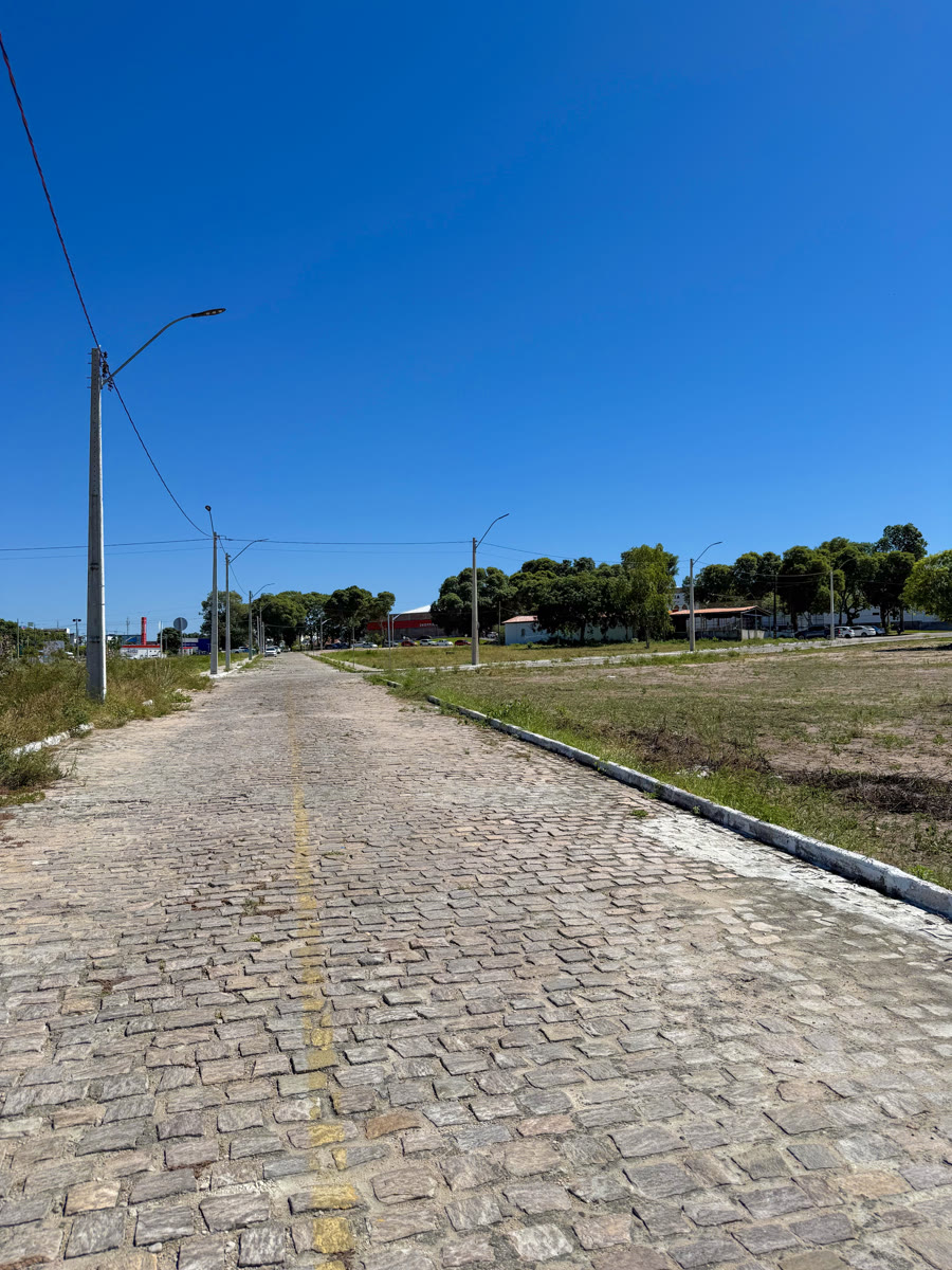 Rua pavimentada com postes de iluminação pública no Vila da Pedra