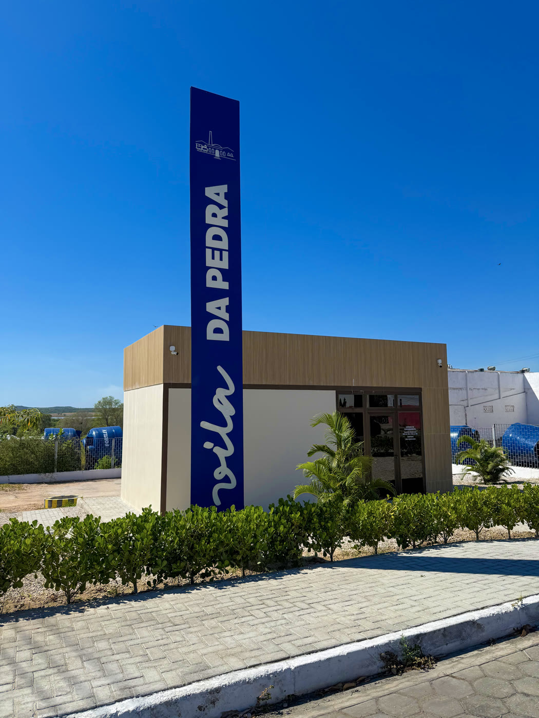 Fachada da sede da Vila da Pedra Empreendimentos com totem azul da marca